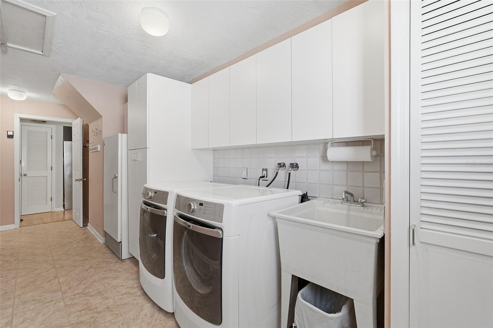 Laundry Room with storage cabinets, laundry sink and extra refrigerator