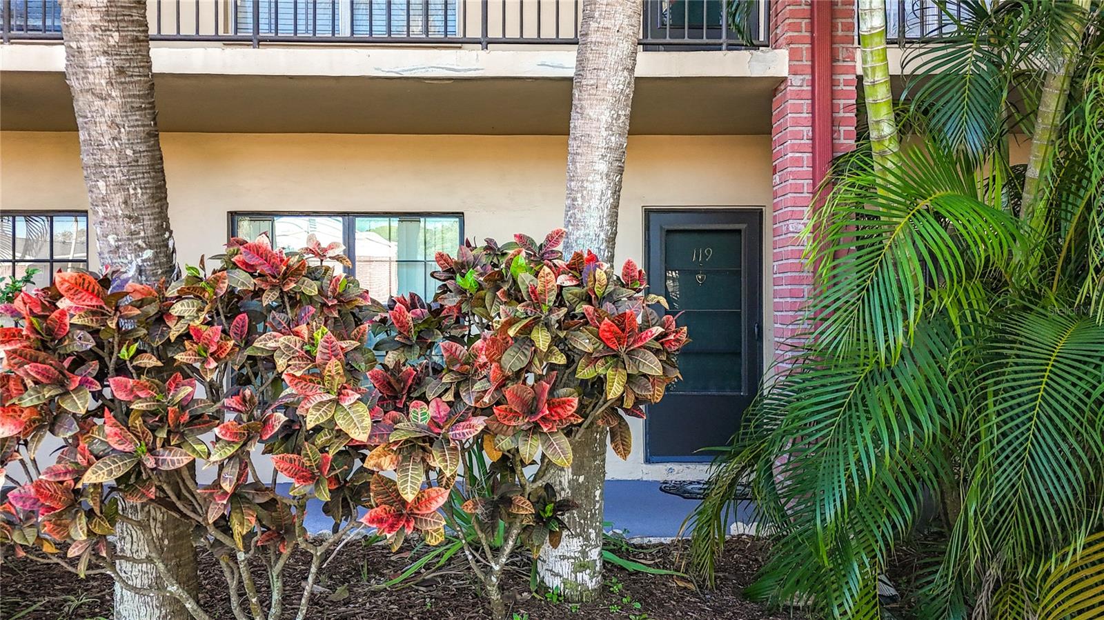 1020 85th Ave N no 119, view of condo from front parking spot. Lots of tropical landscaping.