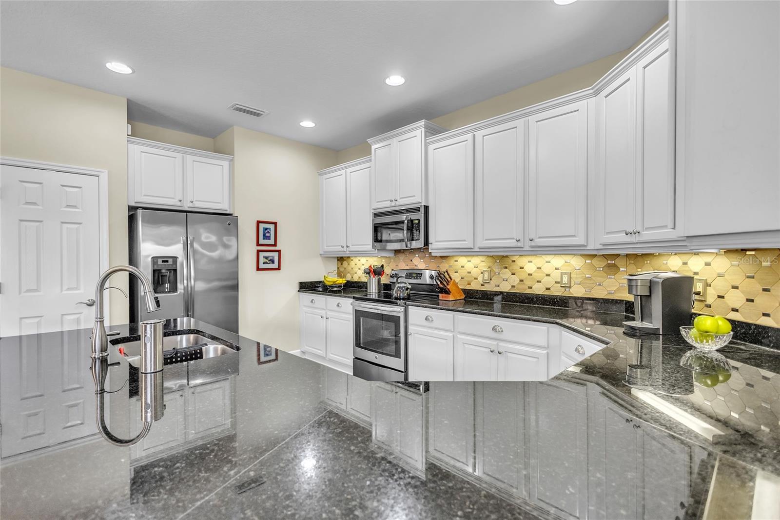Showcase here: abundant granite counter tops, stainless steel appliances, custom backsplash, recessed panel wood cabinets with 36" uppers and an accented raised cabinet bump-out above cook top.