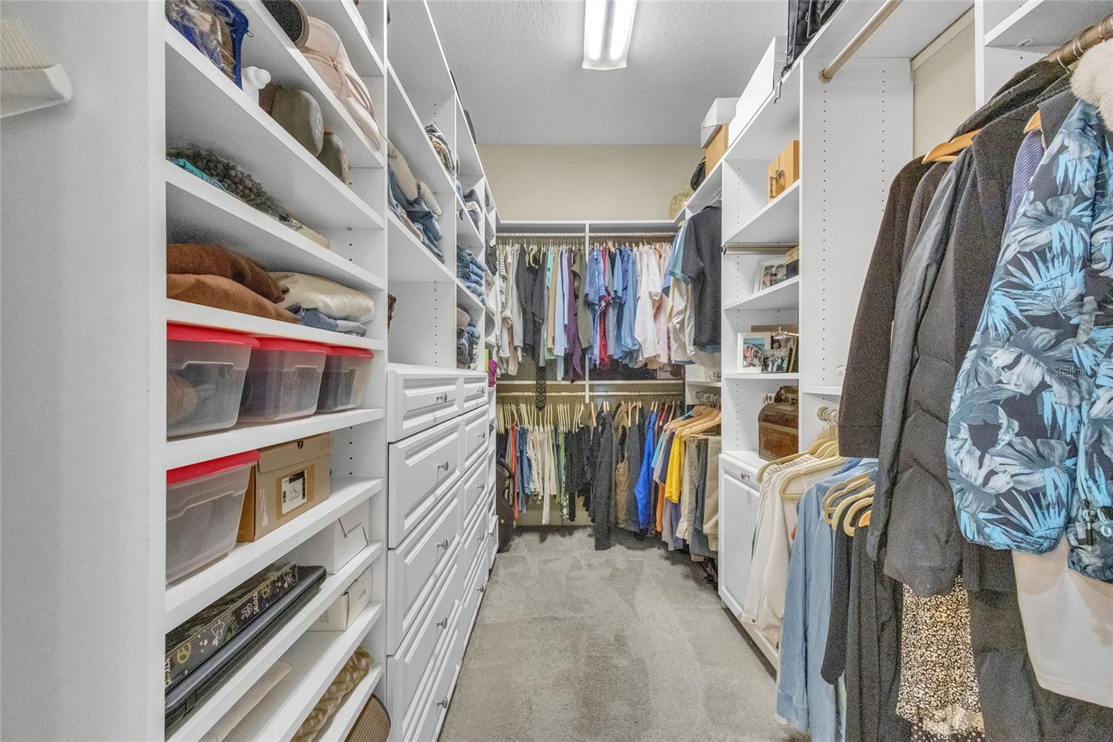 Storage galore in this Owner's walk-in closet featuring custom shelving.