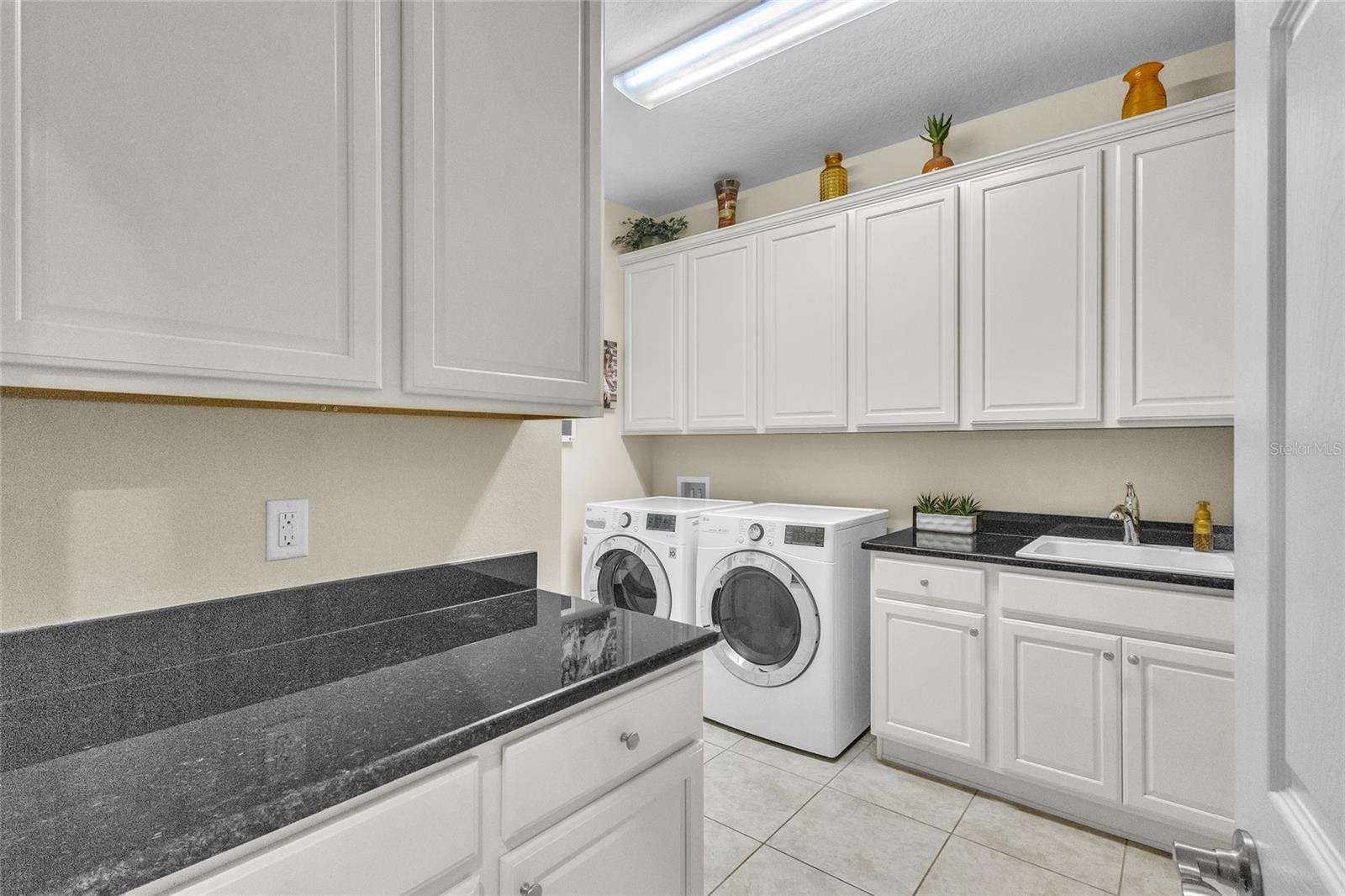 Laundry room with 18" ceramic tile, sink and Energy Star LG washer and dryer. Don't you like the plethora of cabinets vs wire shelves!