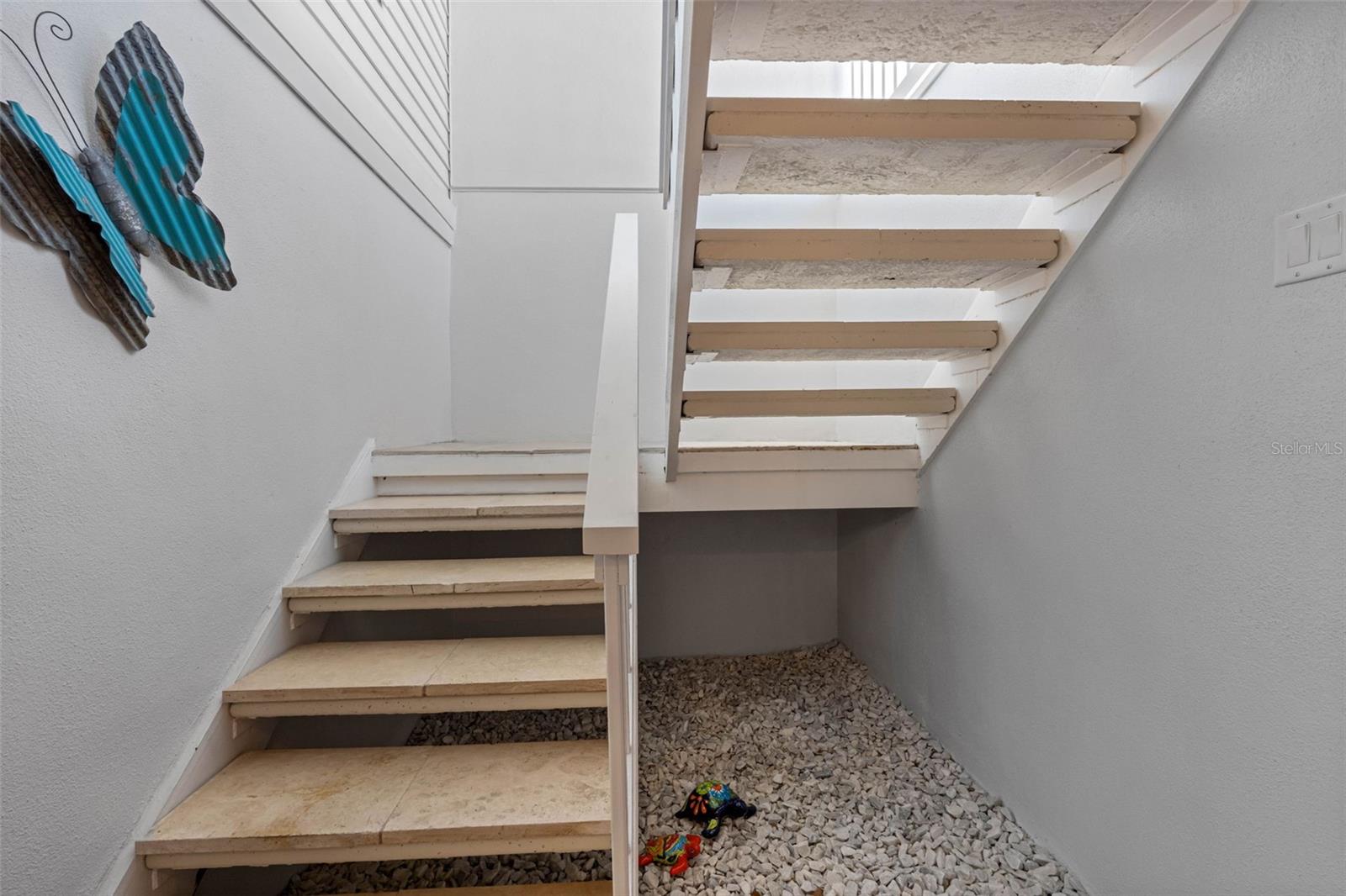 Rock garden below with travertine steps leading to front door.