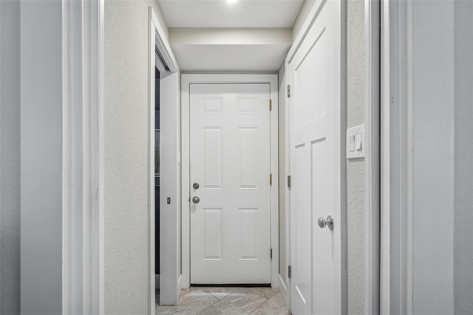 Hallway to half bathroom and the garage with laundry inside