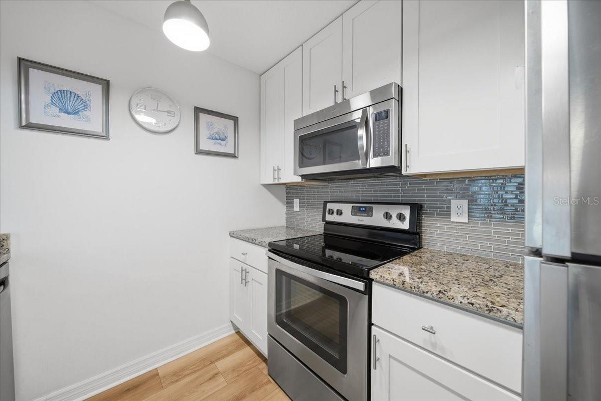 UPDATED KITCHEN with granite countertops, white soft-close cabinets, and stainless-steel Whirlpool appliances.