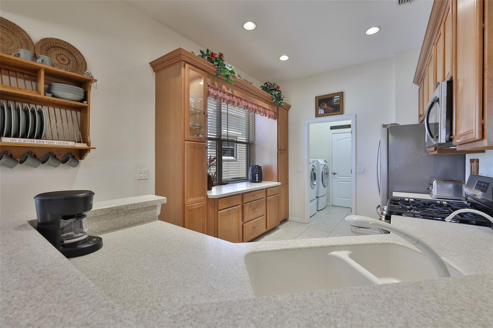 A custom, matching cabinet was built to add additional storage, counter tops and a coffee bar.Notice the recessed lighting and beautiful counter tops.