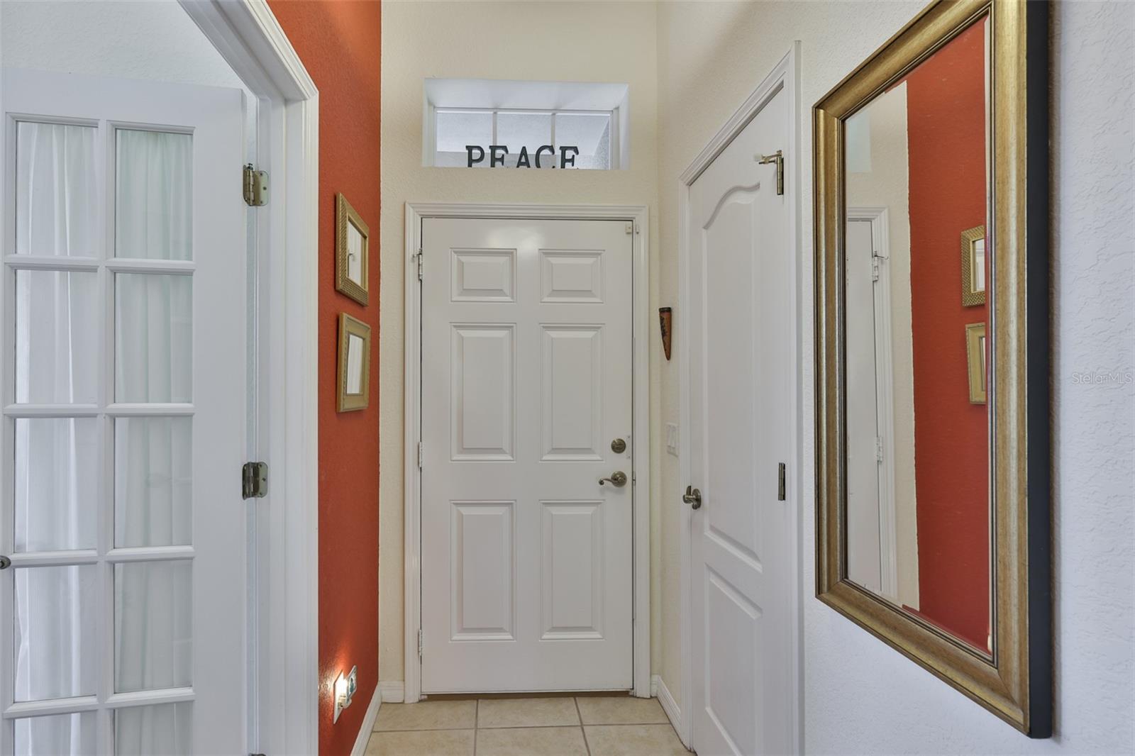 Front foyer with a transom window for natural light and a closet with built in shelving and lighting.