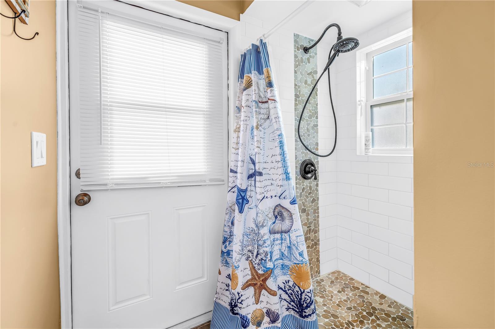 Updated primary bathroom shower and door leading to the pool.