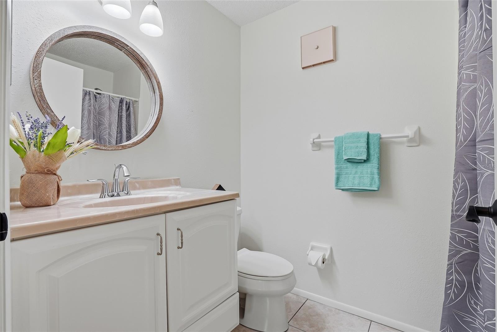 Guest bath with vanity, round mirror, and updated lighting for a clean finish.