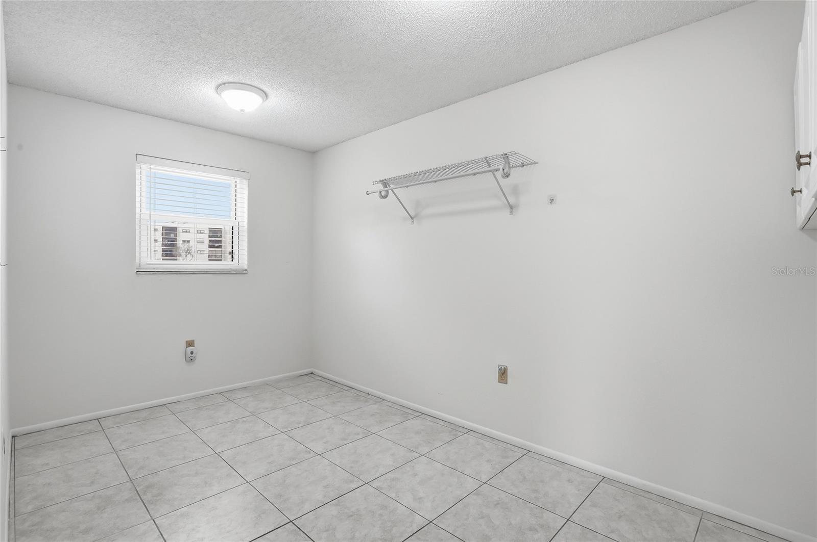 Dedicated large laundry/utility room with tile floors, shelving, and natural light.