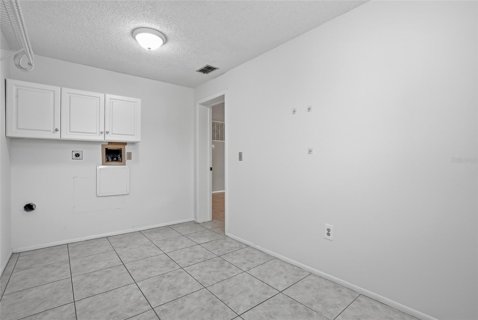 Laundry room with upper cabinetry and washer/dryer hookups—great storage potential.