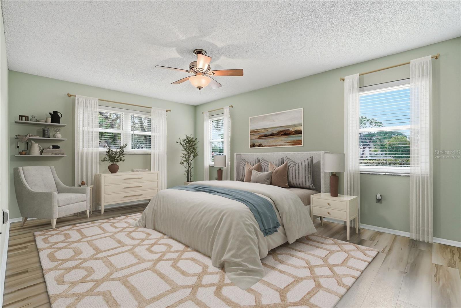Virtually Staged. Light-filled primary bedroom with corner windows and ceiling fan.