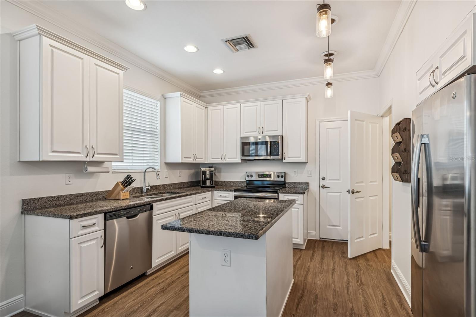 A practical layout with adjacent pantry and storage closets, all unified by wood-style flooring and neutral color palette.
