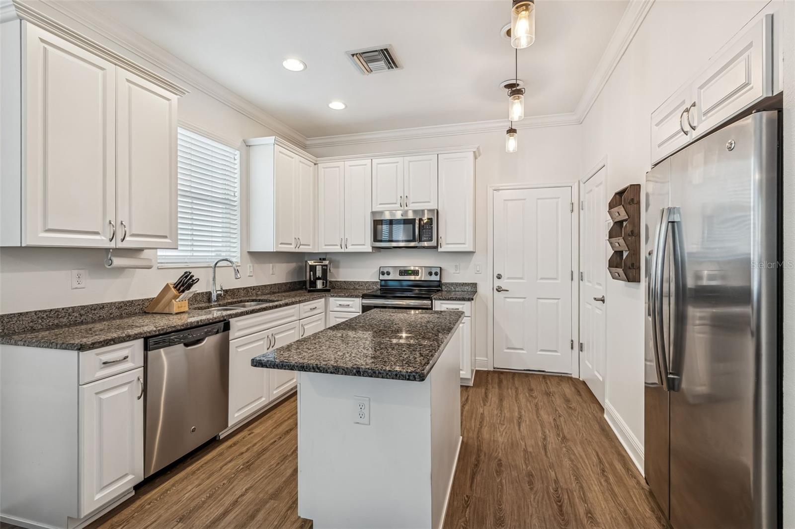 Elegant white cabinets and granite counters contrast beautifully with the warm flooring; ideal for everyday living or entertaining.