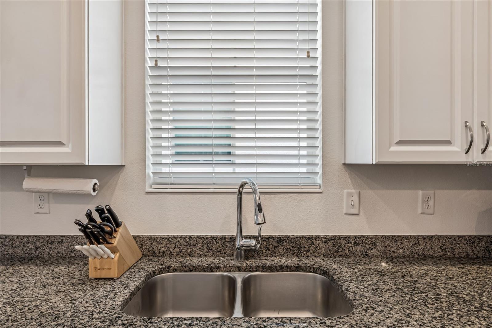 Sunlight streams in through the kitchen window, brightening the prep area and enhancing the overall airy feel.