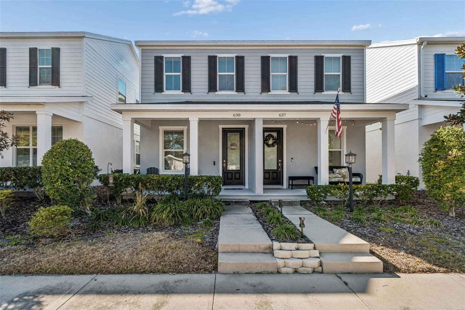 Well-maintained front entry with dual-pane windows and tasteful black door framed by crisp white trim and pillars.