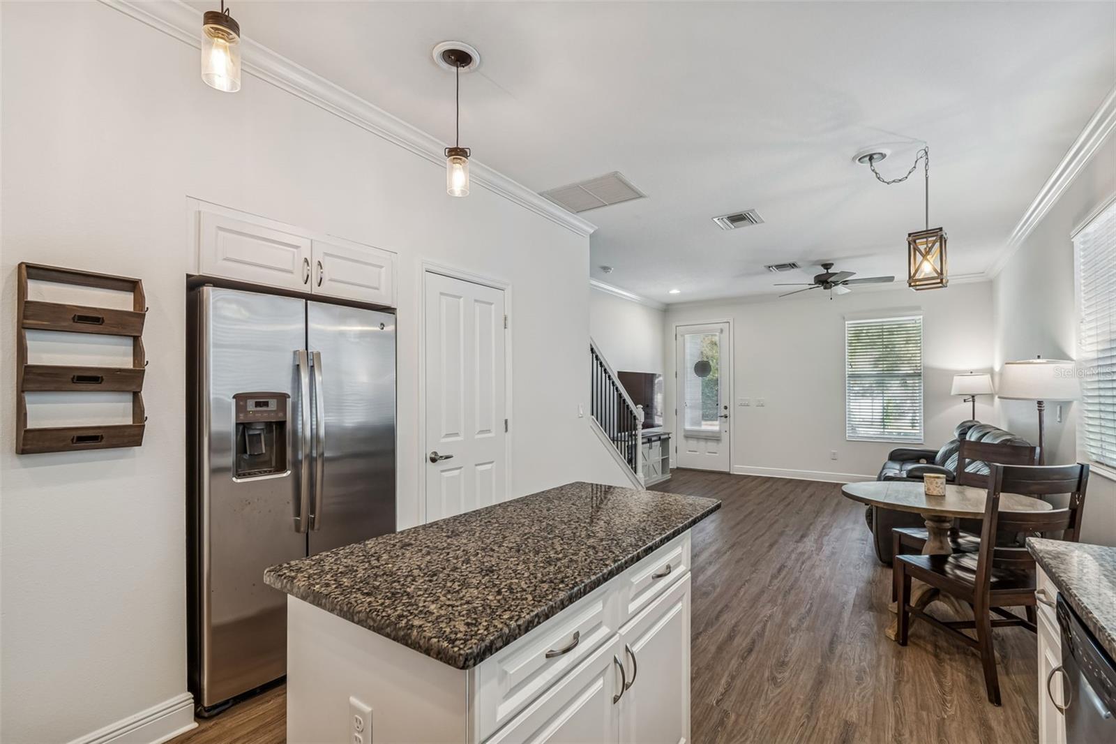 Island-centered design offers seamless access to living and dining areas, with crown molding and recessed lighting adding a polished finish. Don't miss the DEEP pantry next to the refrigerator.