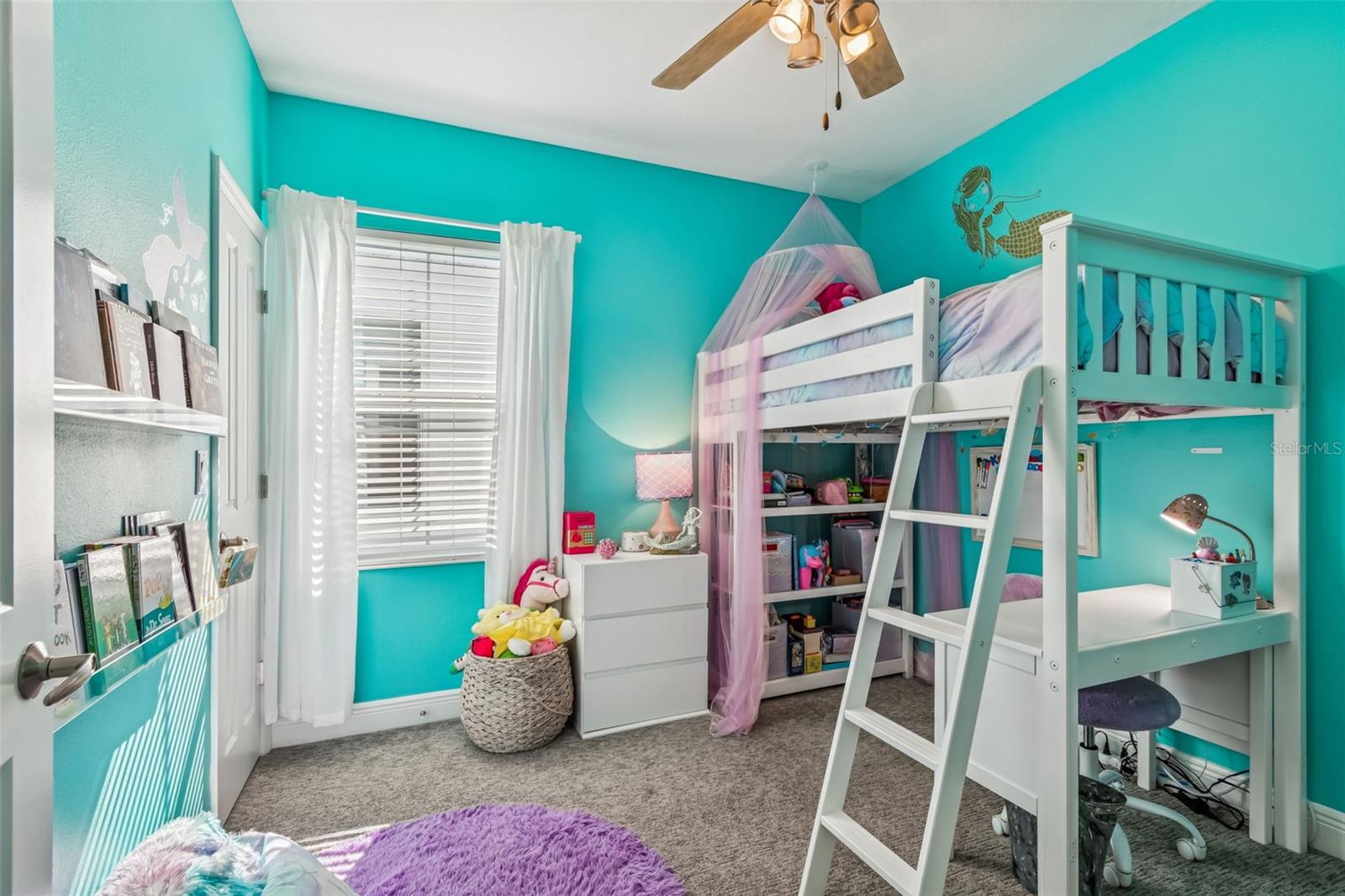 Bright and creative space perfect for play or study, complete with cozy carpeting and white-framed windows with sheer drapes.