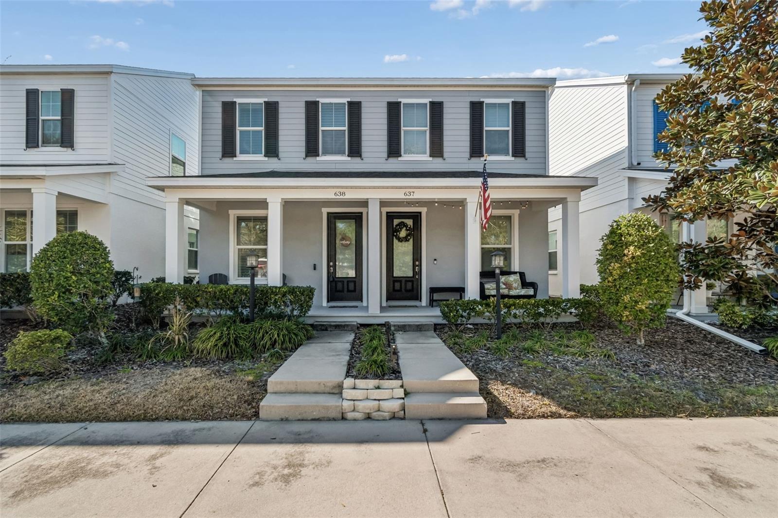 Sidewalk-facing home with easy front access, enhanced by mature landscaping and dual lantern-style light posts.