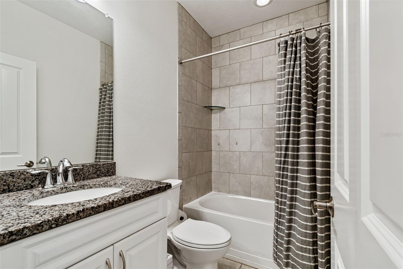 Sleek and functional with updated fixtures, tile surround, and plenty of cabinet storage.