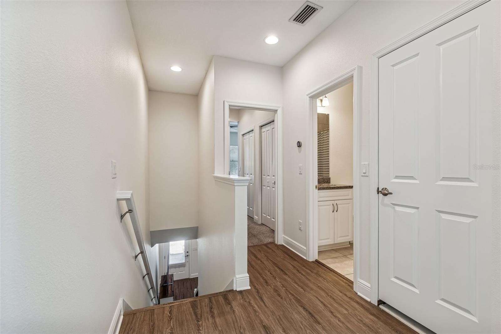 Stacked LG washer and dryer tucked into a convenient second-floor laundry closet with shelving above.