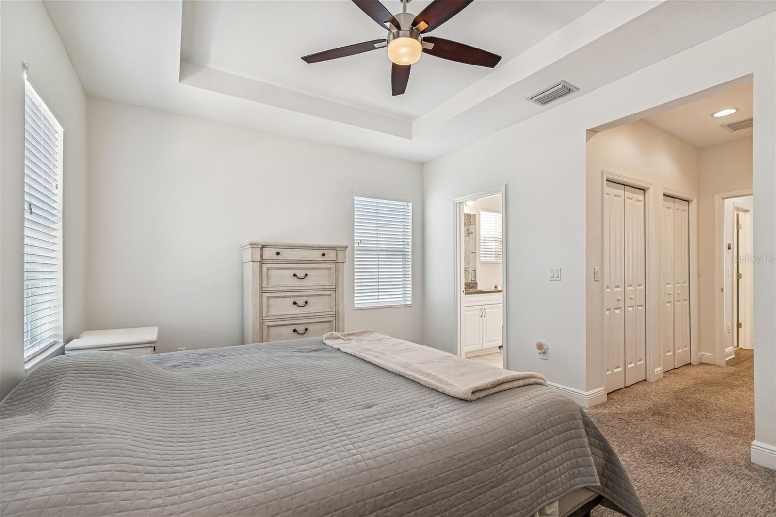 A peaceful owner’s retreat with ceiling fan, neutral tones, and direct access to the en-suite bath and closet space.