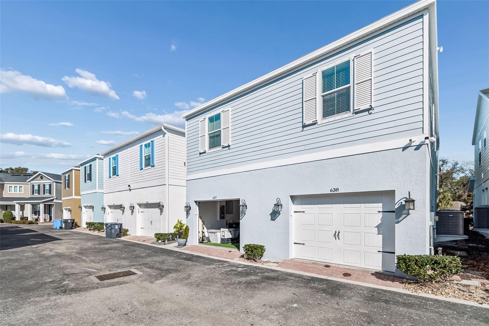 Rear-facing 1-car garage with carriage-style door, enhanced by modern lantern lighting and low-maintenance landscaping.