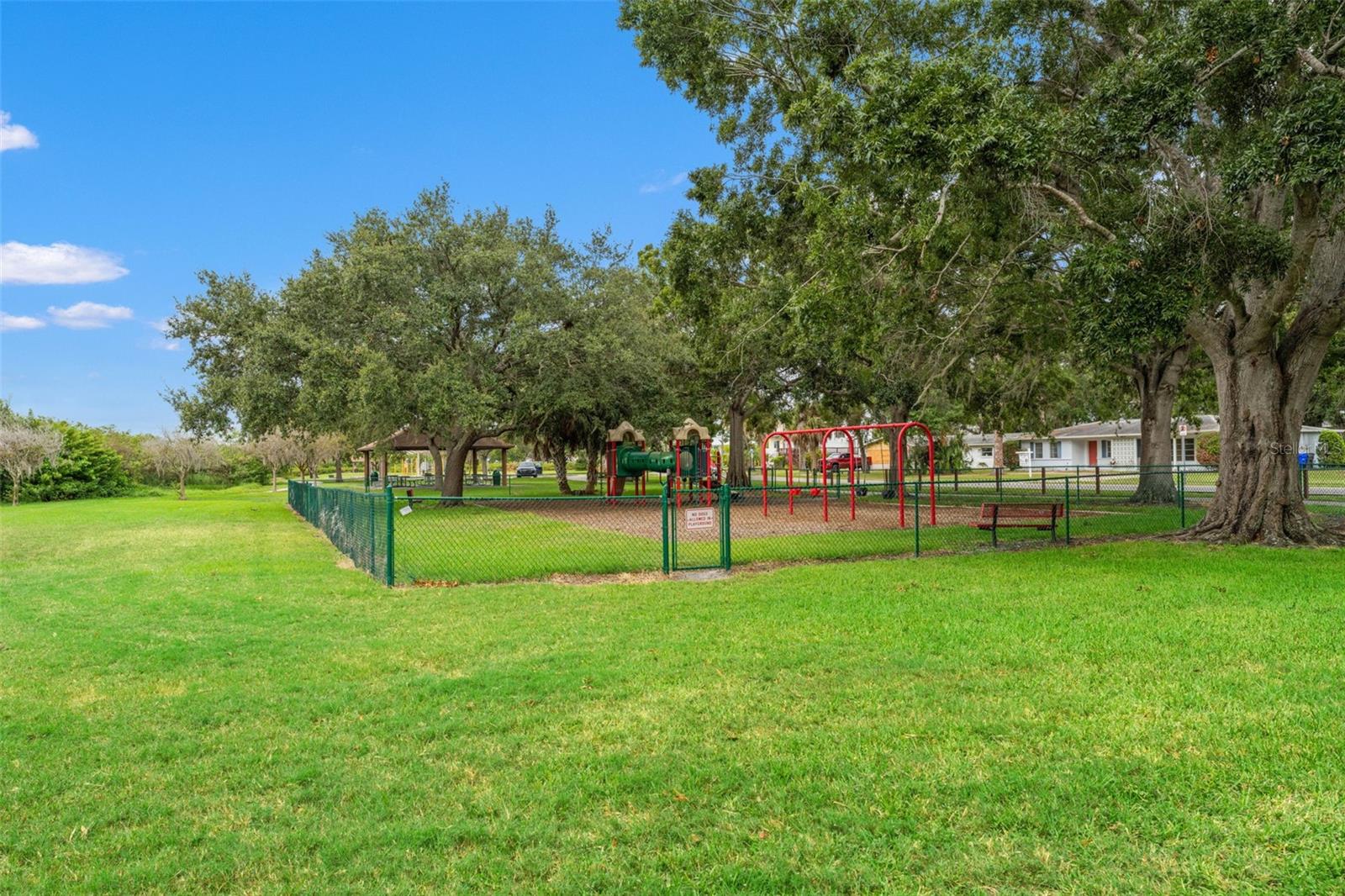 Shaded playground surrounded by mature oaks, complete with swings and play structures—perfect for families and weekend fun.