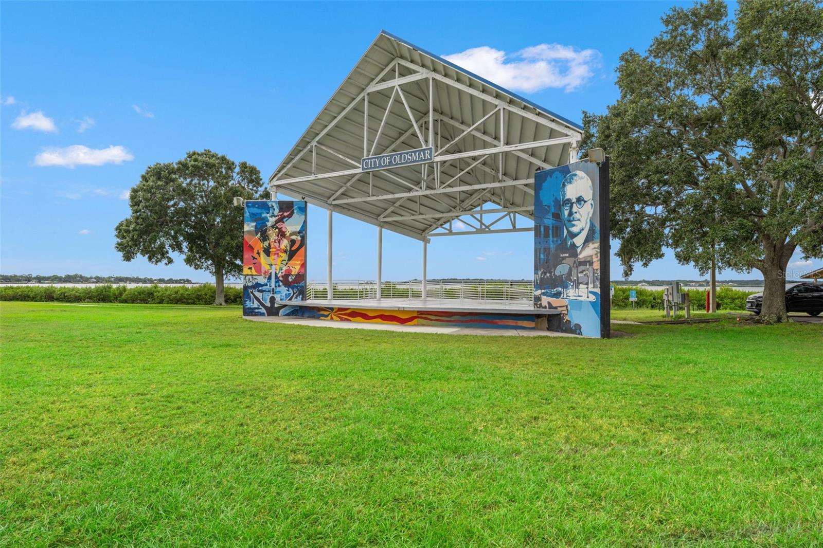 Charming open-air pavilion with colorful murals in the heart of R.E. Olds Park—ideal for concerts, community events, and weekend relaxation.