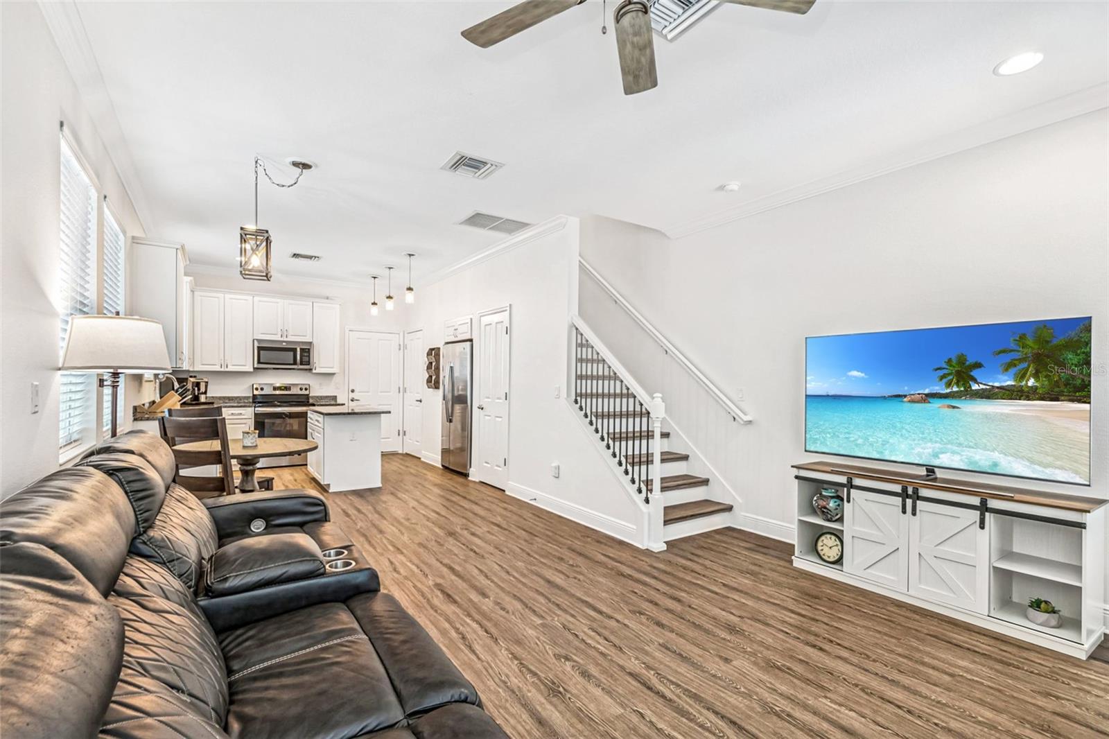 Stylish open floor plan featuring luxury vinyl plank flooring, white shaker cabinets, granite counters, and pendant lighting—perfectly uniting the kitchen, dining, and living spaces.