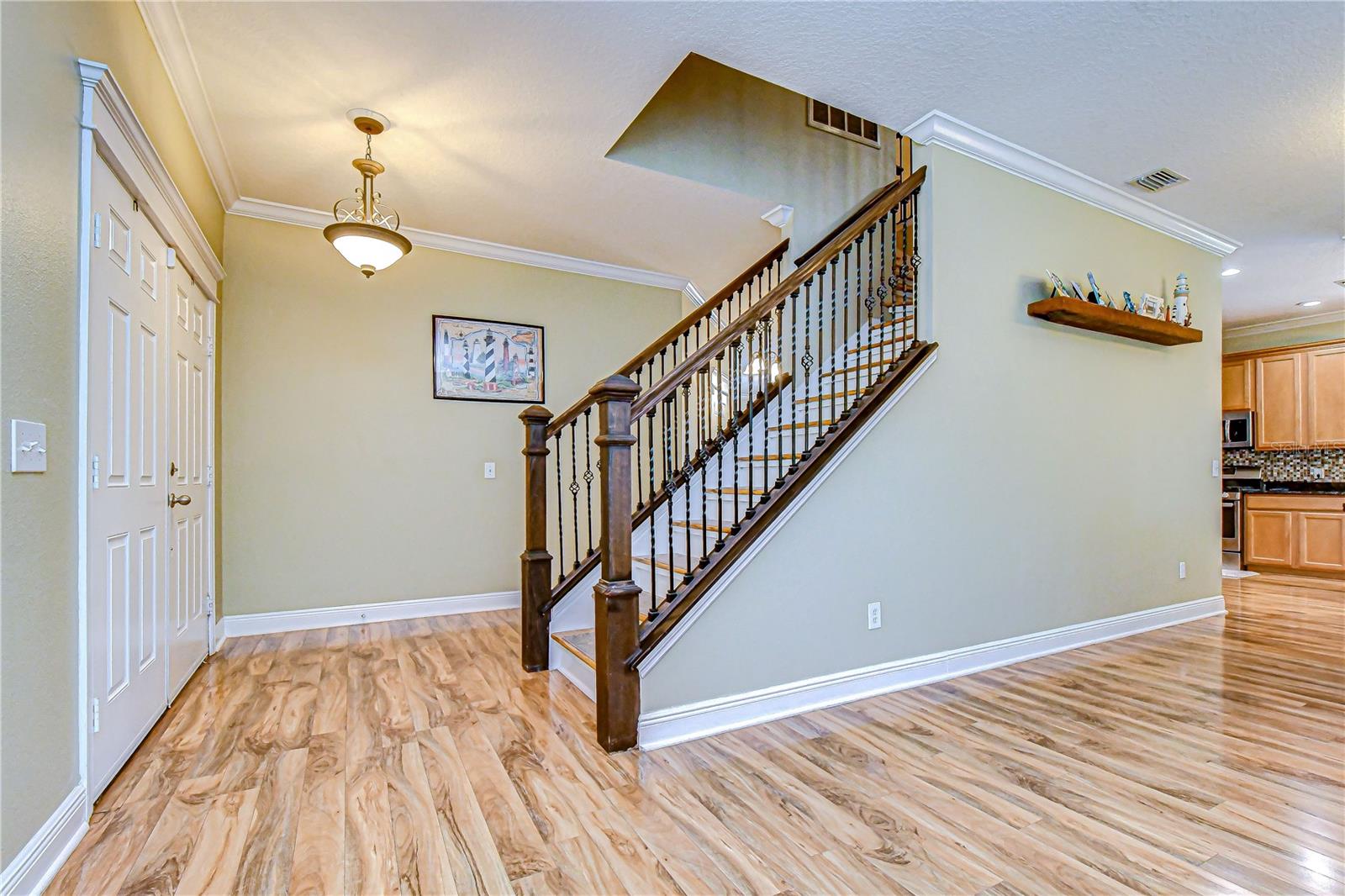 Light-filled entryway showcases rich floors, crown molding, and a striking staircase with iron balusters!
