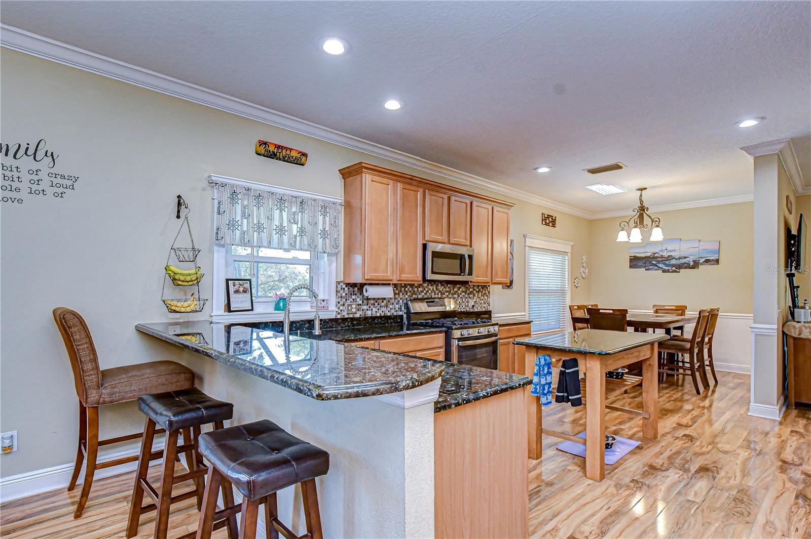 Bright, open kitchen with granite counters, warm wood cabinetry, and inviting breakfast bar!