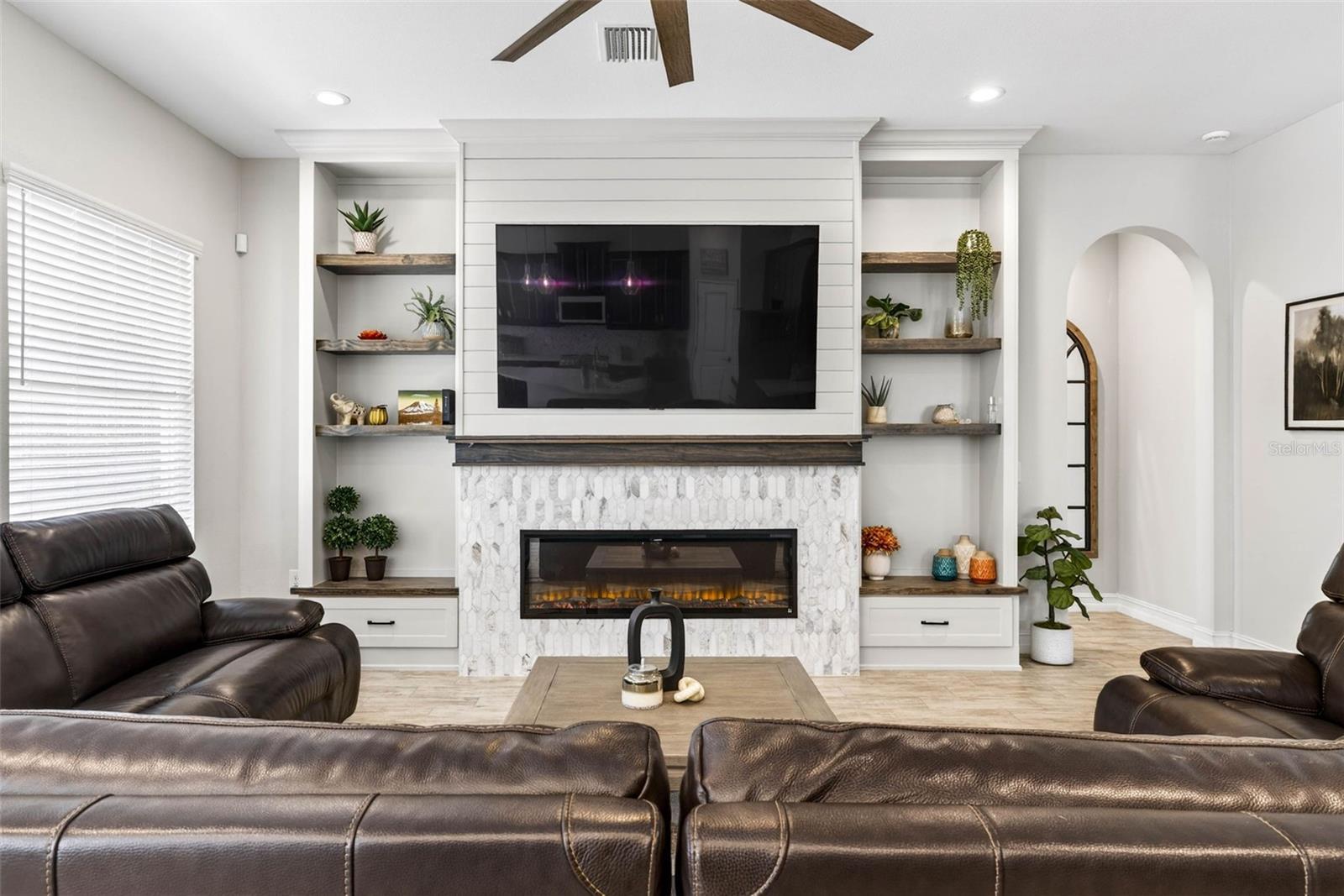 An electric fireplace with tv mount and shelving adorns the living room wall.