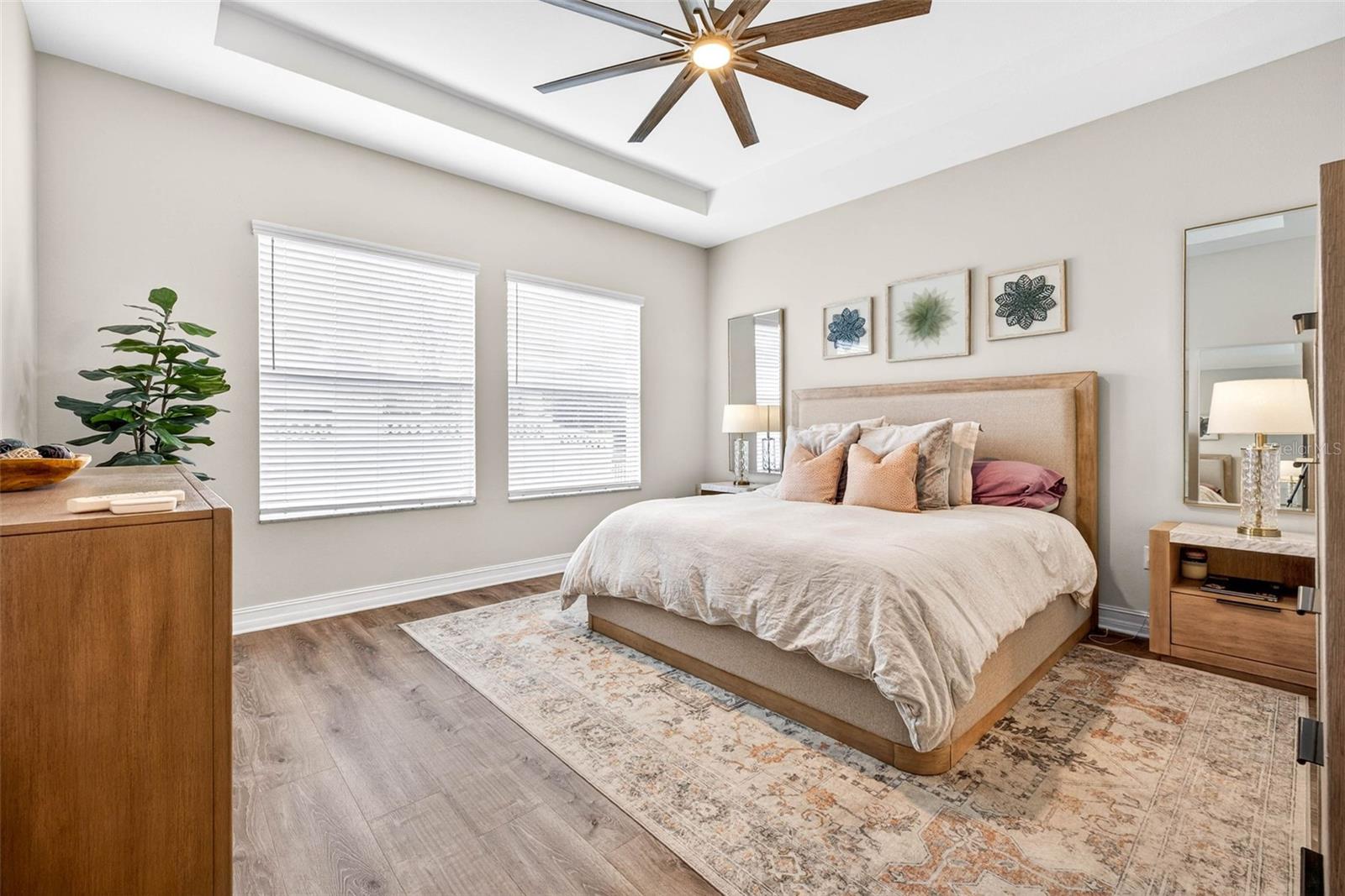 Your primary suite with tray ceiling faces the backyard view.