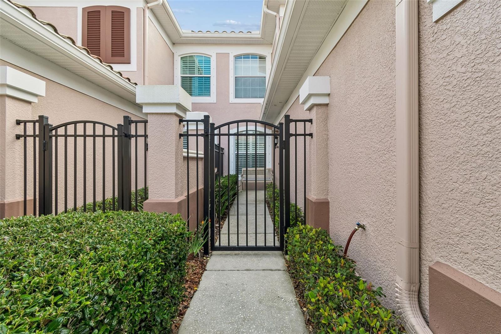 A charming wrought-iron gate and manicured hedges welcome you into this private, courtyard-style entrance.