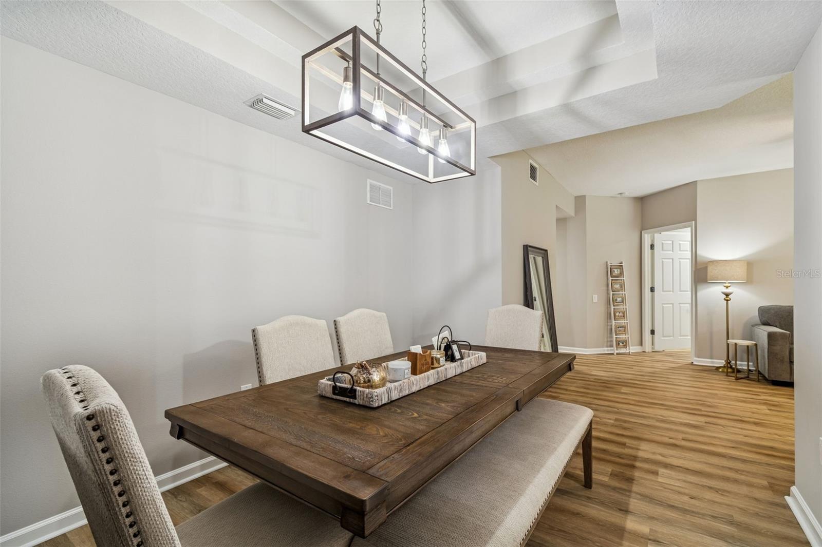 The dining area offers seamless flow to the living room, with layered ceiling design and stylish wood furnishings.