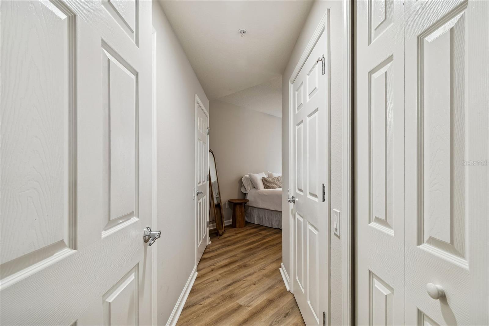 Step into the private entry hall of the primary suite, where dual closets and wood-style flooring create a seamless transition into your personal retreat.