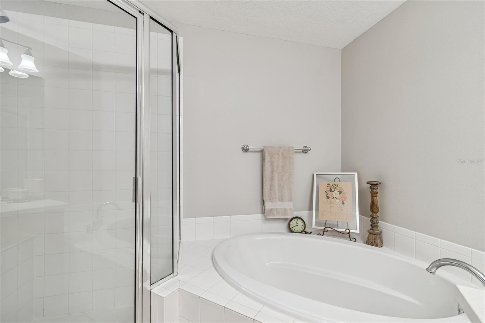 A sleek glass-enclosed shower complements the soaking tub, offering a bright, modern space for everyday convenience.