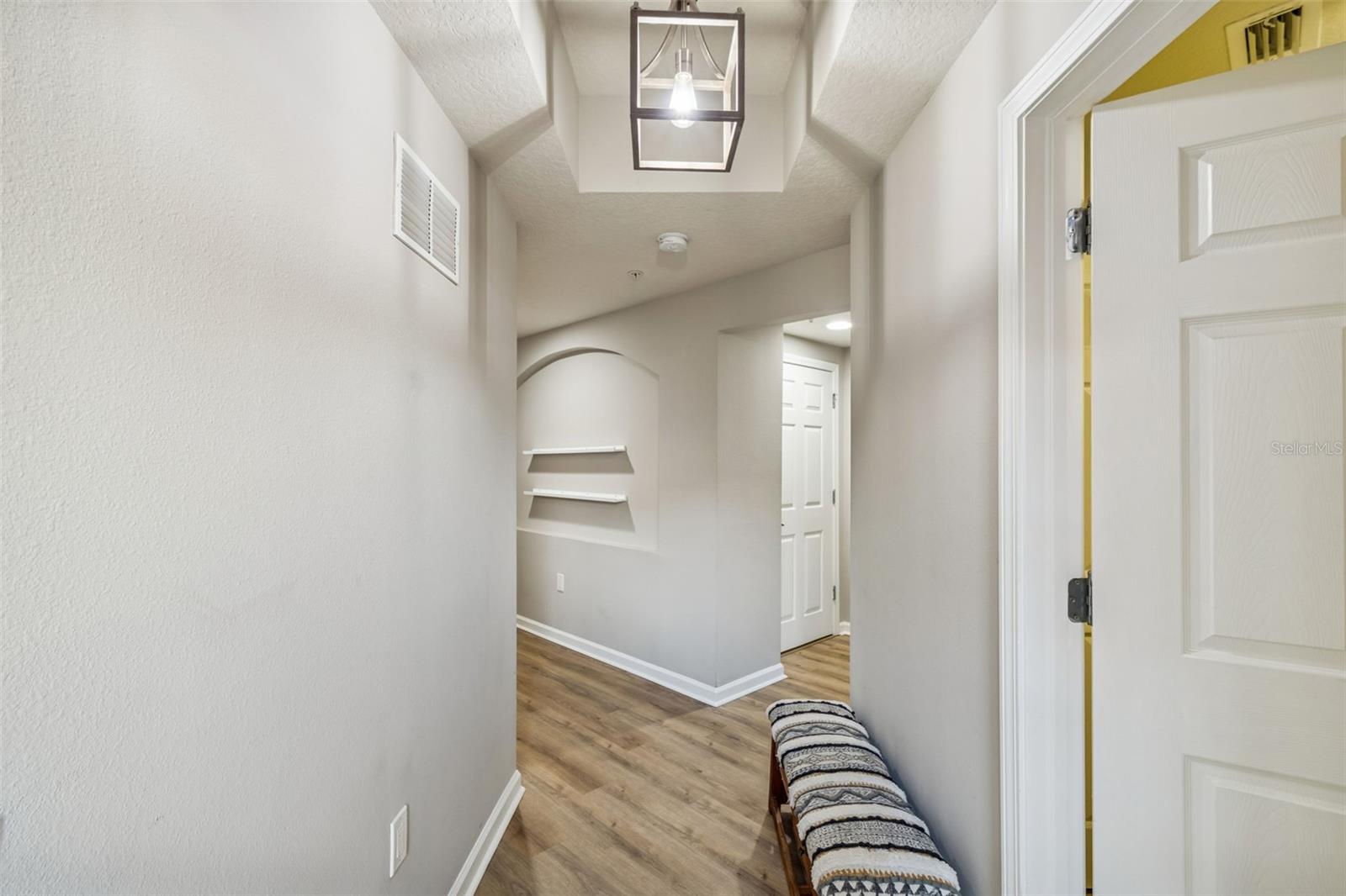 Step into a bright and airy hallway with soft neutral walls, tray ceiling detail, and wood-look flooring that flows throughout.
