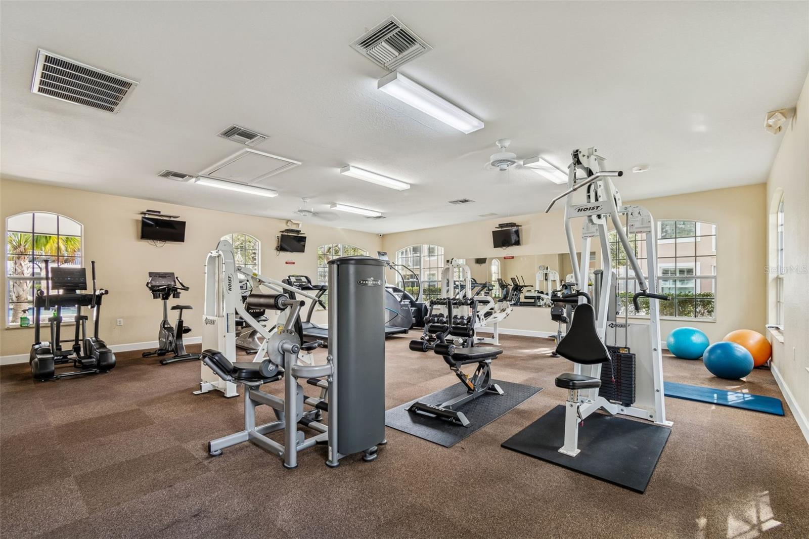 This fully equipped gym boasts a variety of cardio machines and weight training equipment, all in a sun-drenched space with large windows, mirrored walls, and mounted flat-screen TVs for added convenience and motivation.