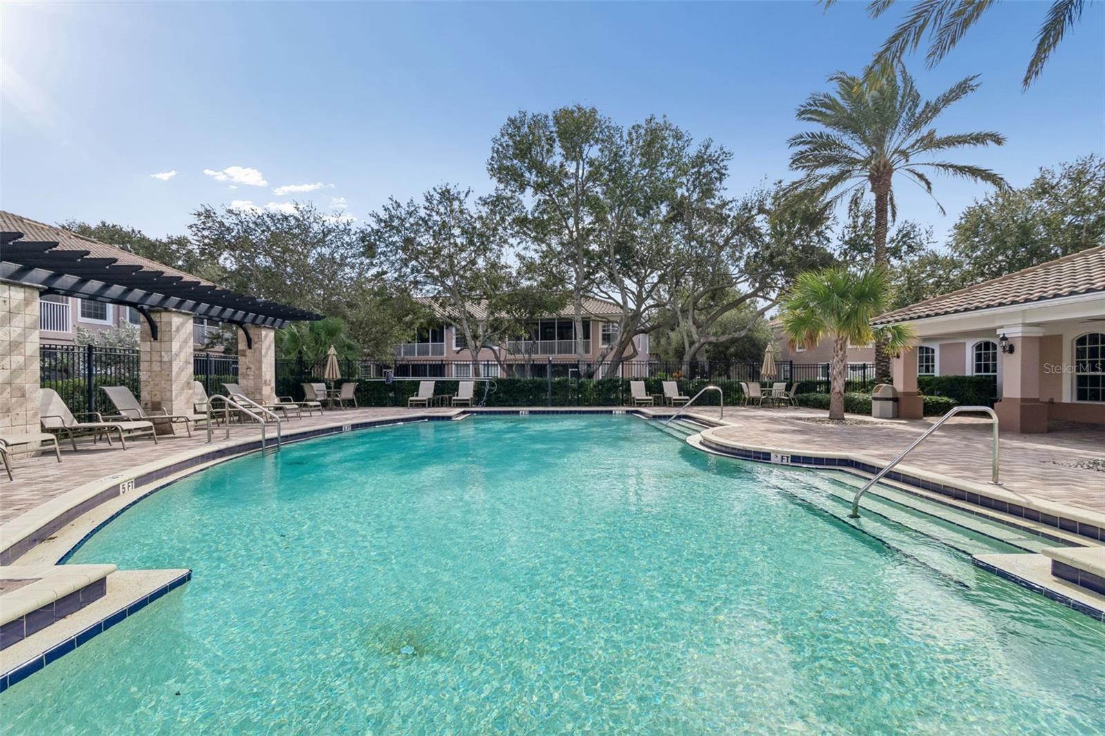Dive into this beautifully maintained pool, set amidst manicured landscaping and swaying palm trees. Lounge chairs and umbrellas create the perfect oasis for sunbathing or socializing with neighbors.