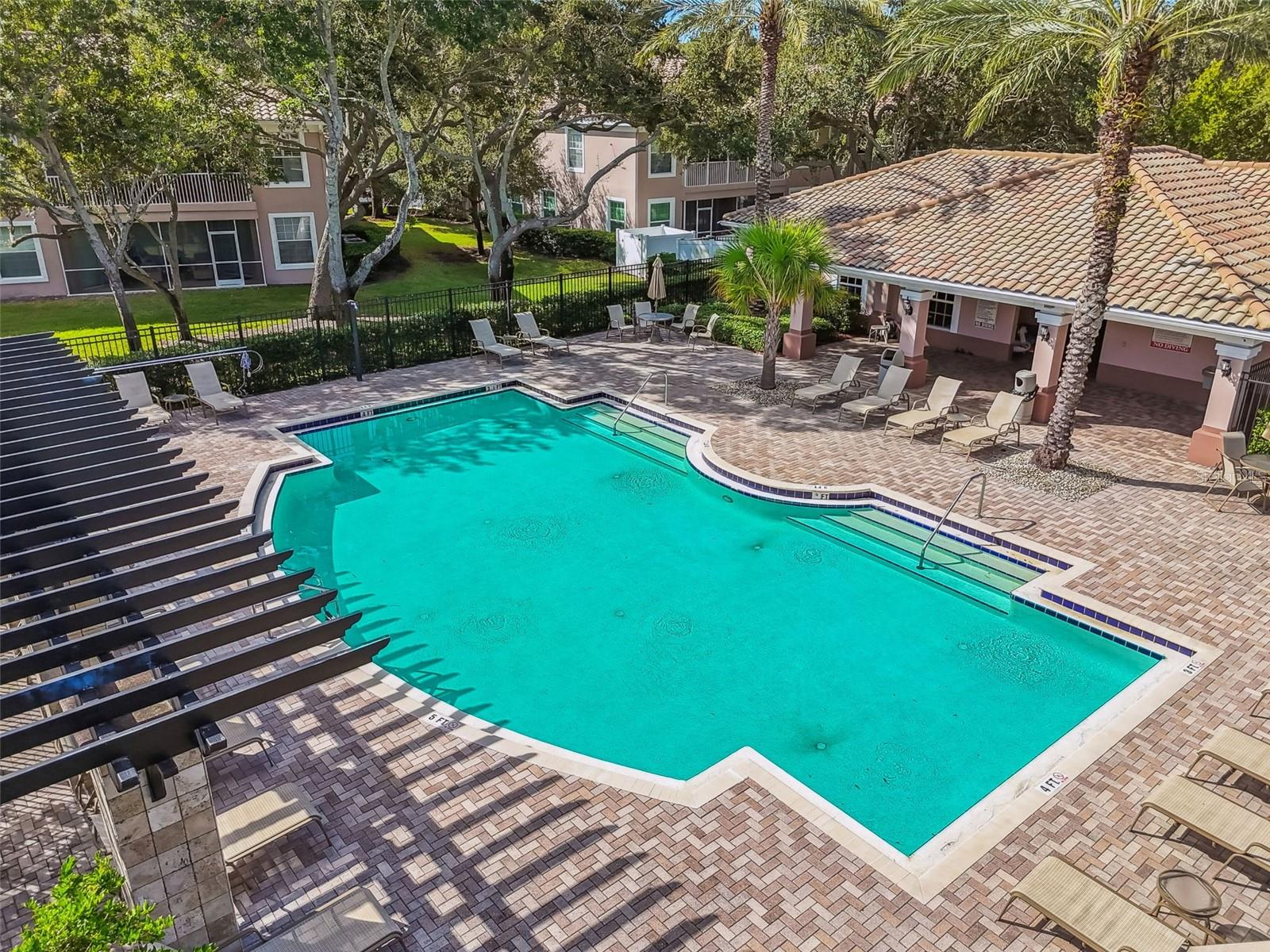 Dive into tranquility with this sparkling, resort-style pool framed by paver decking, loungers, and charming stone-columned pergolas—perfect for relaxing under the Florida sun.