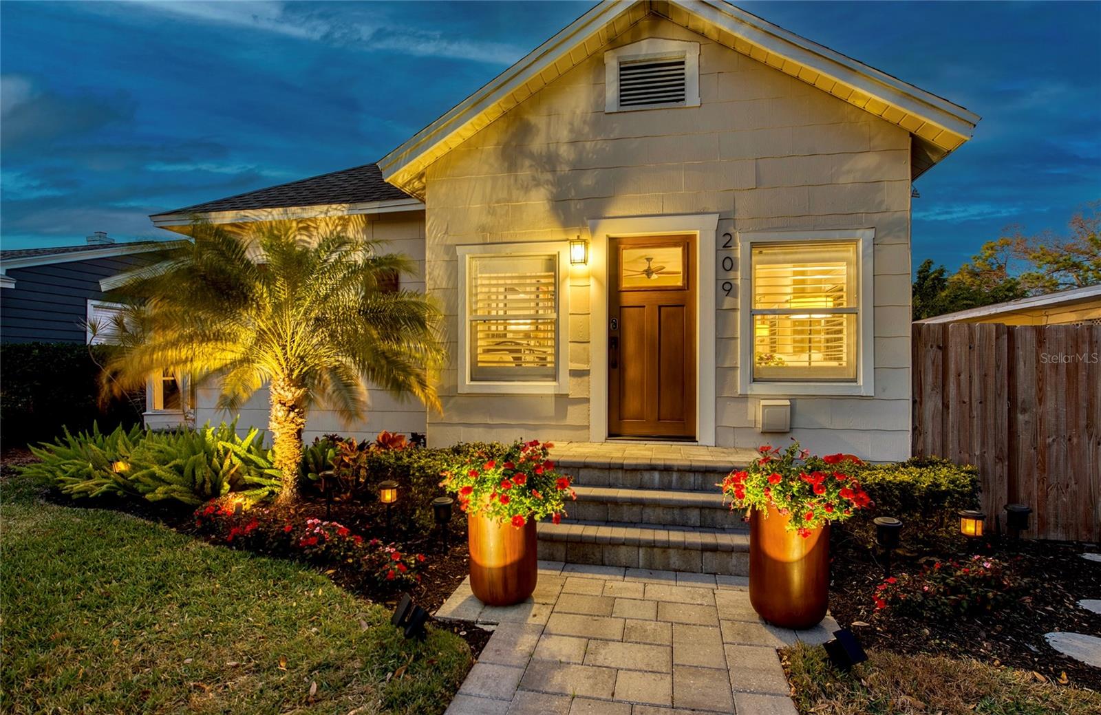 Beautifully curated landscaping is enhanced with tasteful exterior lighting- a warm welcome home!