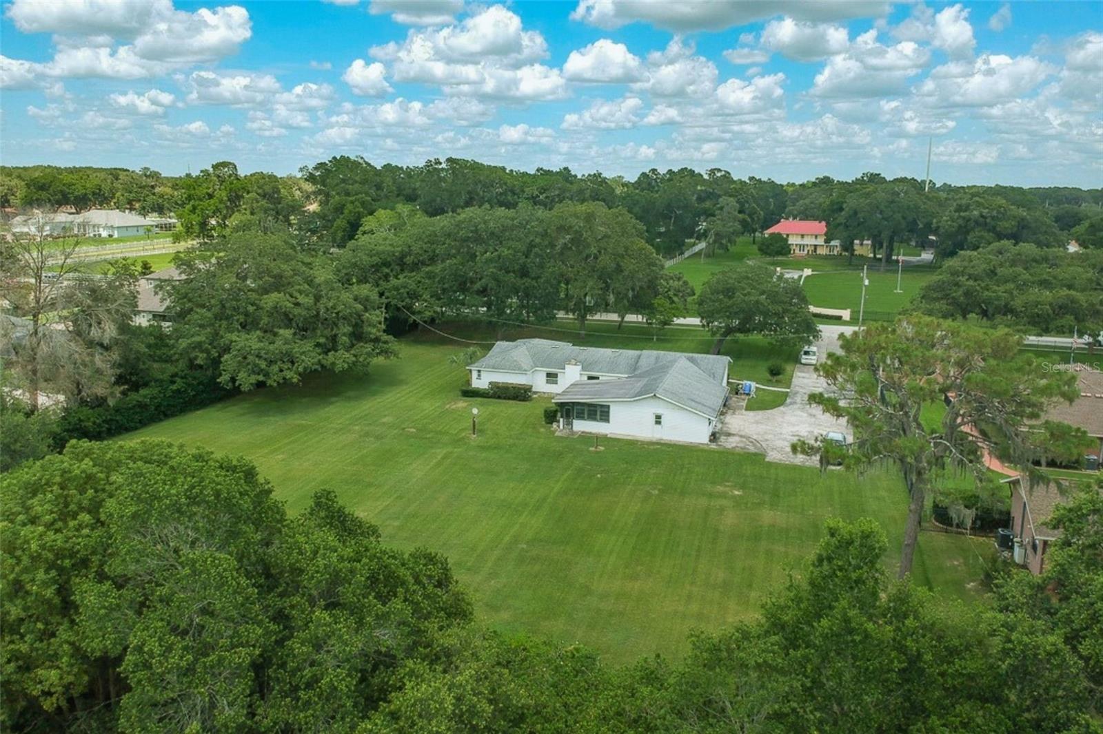 Rear aerial view highlighting expansive backyard and overall property scale.