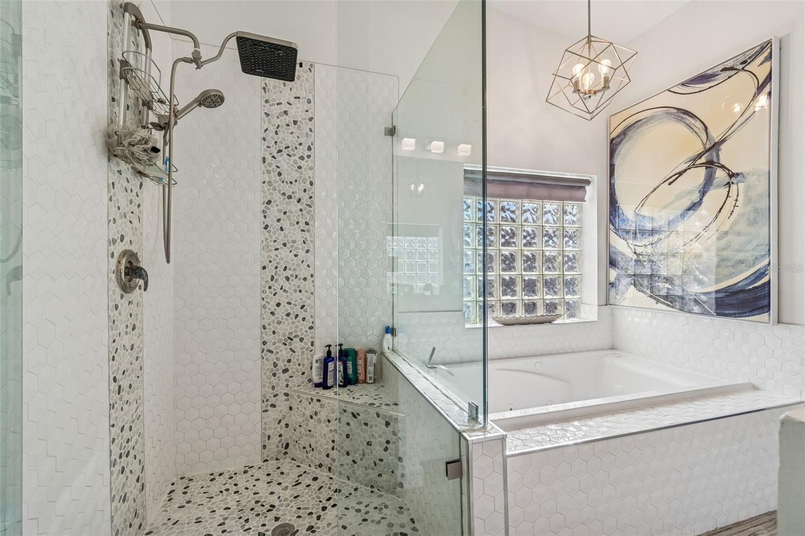 Bright spa-like bathroom with walk-in glass shower, rainfall head, soaking tub, and modern finishes.