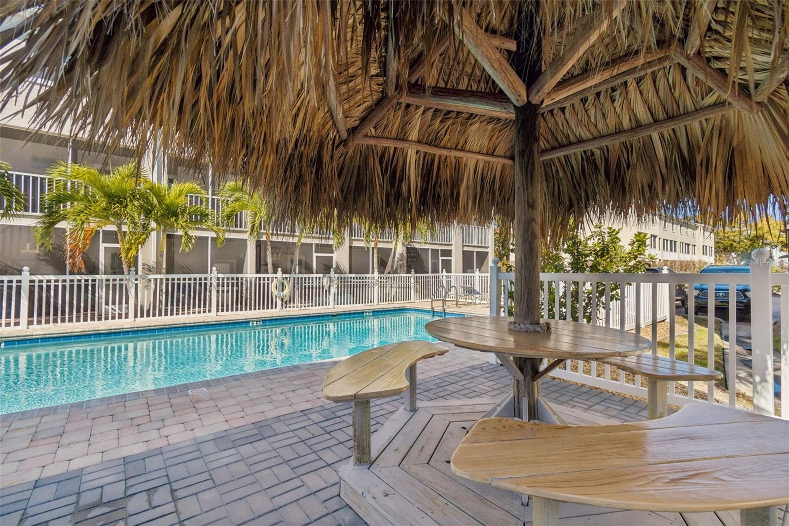 Resort-style community pool with tropical tiki seating area, perfect for relaxing and entertaining.
