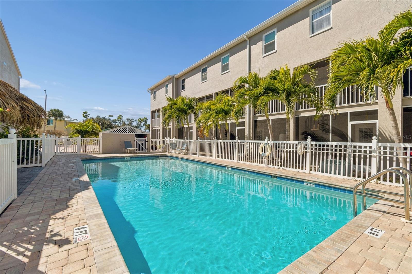 Resort-style community pool with tropical tiki seating area, perfect for relaxing and entertaining.