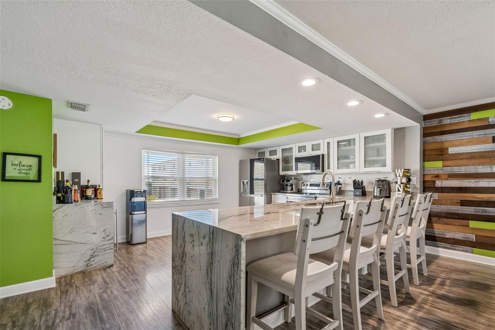 Updated kitchen with quartzite waterfall island, designer tile accents, and bar seating — perfect for entertaining.