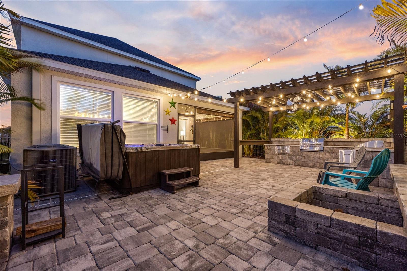 Private outdoor living designed for year-round enjoyment — screened patio, pergola-covered outdoor kitchen, fire pit, and hot tub all ready to enjoy.
