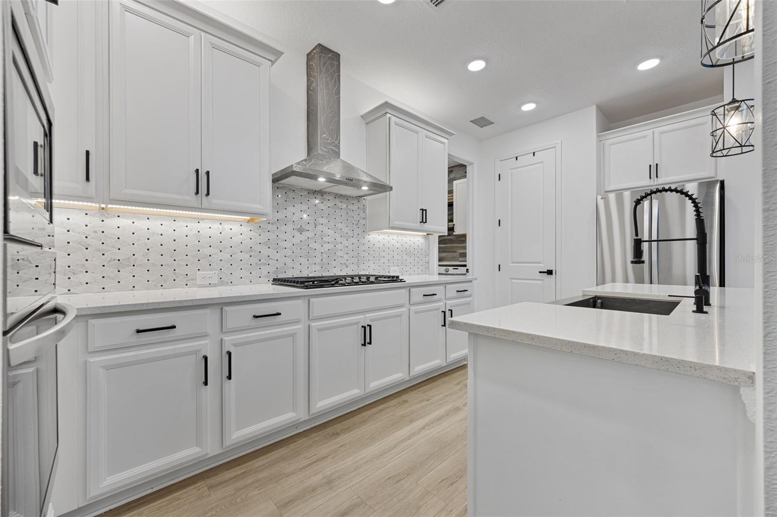Open-concept kitchen featuring Smart LG appliances, farmhouse sink, gas cooktop, and seamless flow into the main living area.