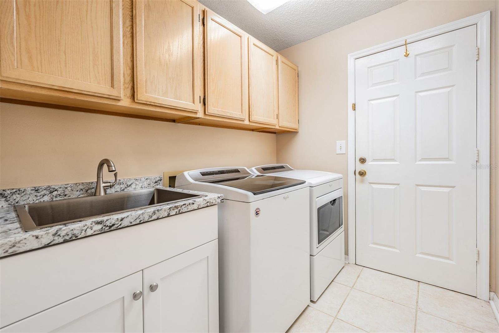 Laundry room with cabinets above